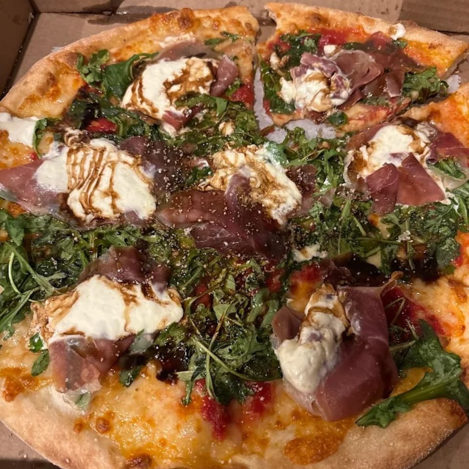A whole That's Italian Pizza with prosciutto, fresh mozzarella, arugula, and balsamic glaze.